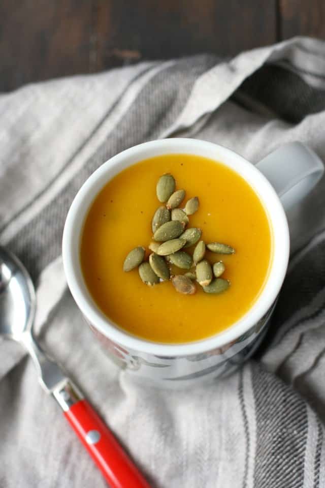dairy free squash soup in a cup with a red handled spoon