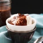 chocolate fudge sauce on ice cream in a small white bowl