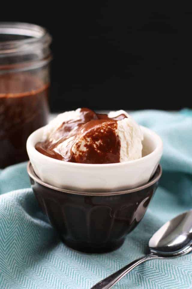 chocolate fudge sauce on ice cream in a small white bowl