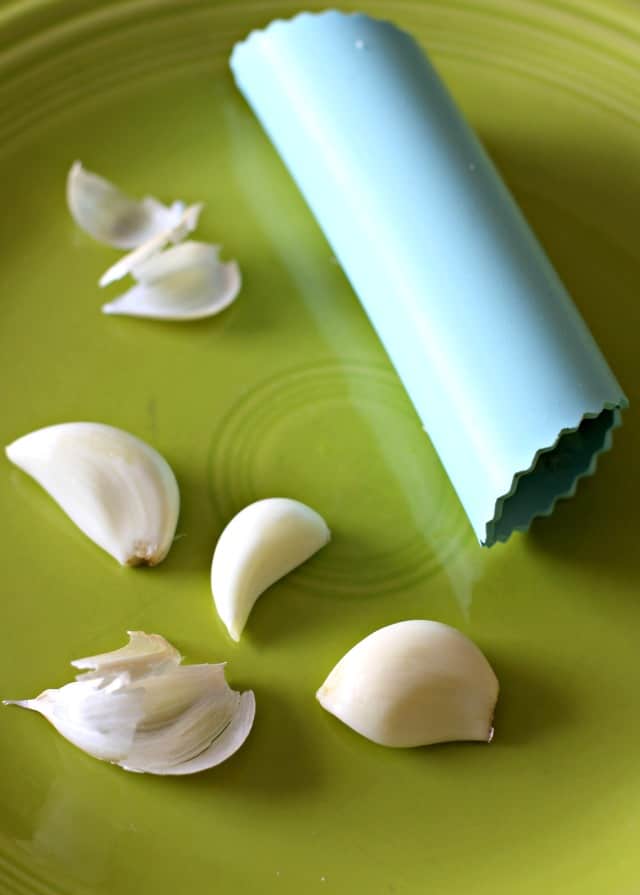 garlic cloves on a plate with a garlic peeler