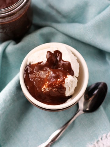 vegan chocolate sauce on vanilla coconut ice cream in a white bowl