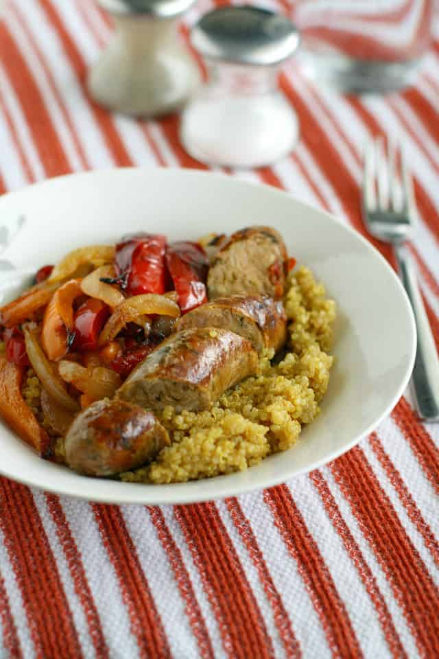 curry spiced quinoa with sausages and peppers on a white plate