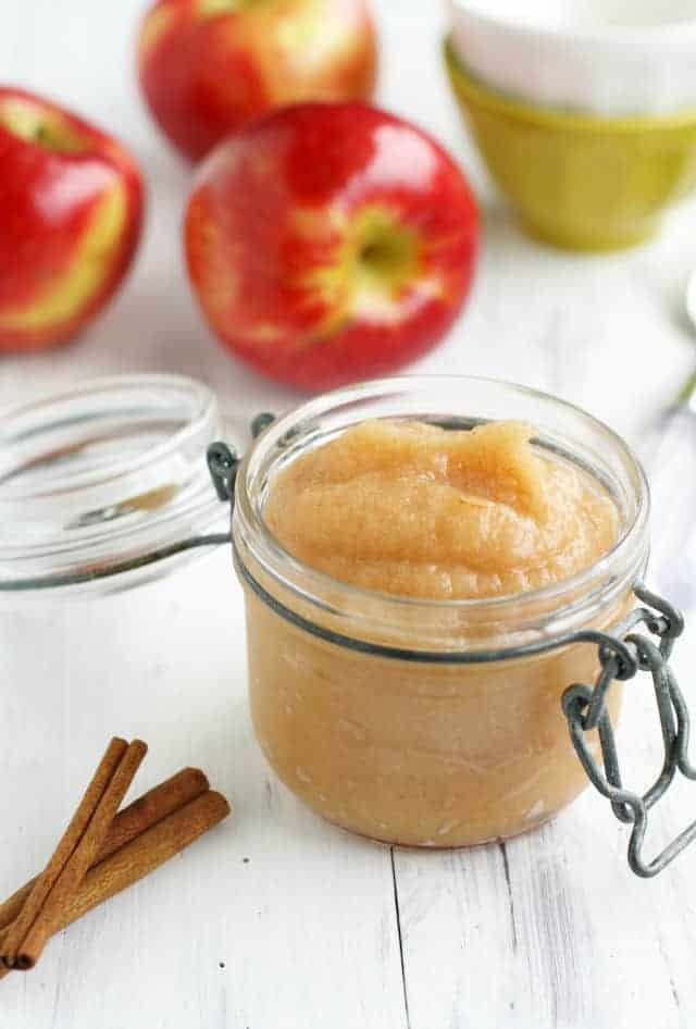 cinnamon applesauce in a small mason jar with apples in the background