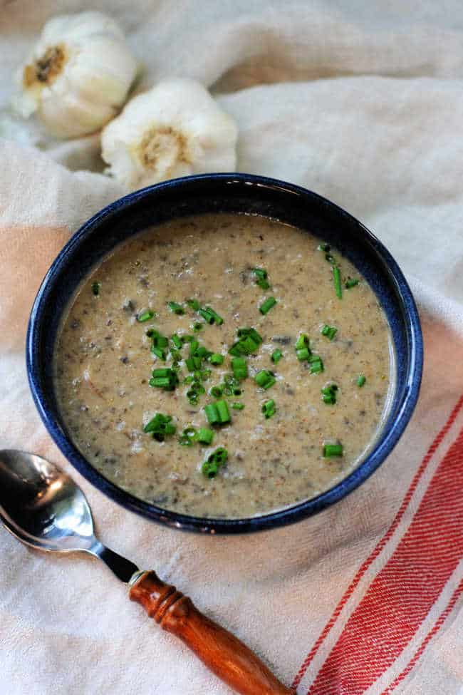 vegan mushroom soup in a blue bowl with a wooden spoon