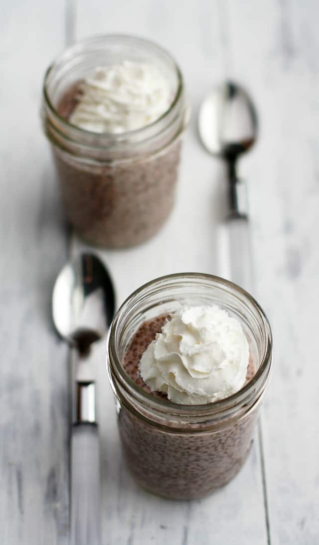 strawberry chia pudding topped with whipped cream in glass jars