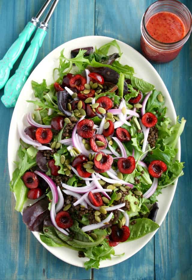 white tray with a green salad with cherries and lentils