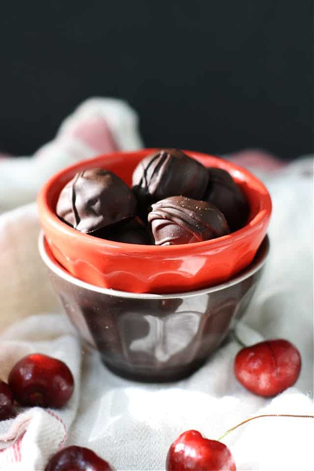 dark chocolate covered cherries in a red bowl