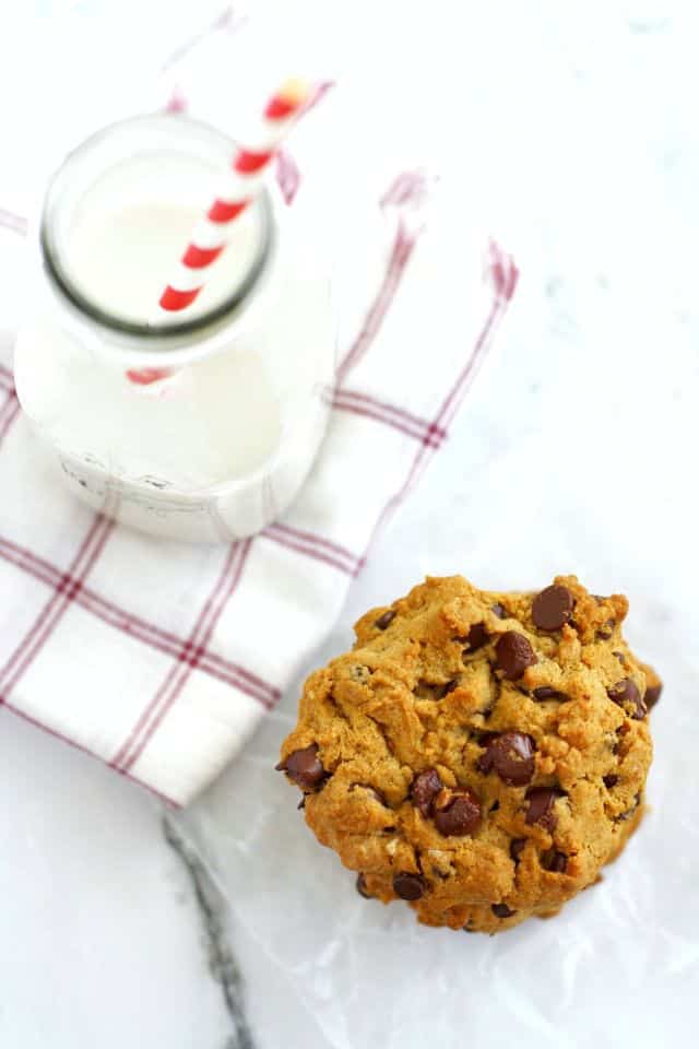 chocolate chip cookie on a napkin with a bottle of milk next to it