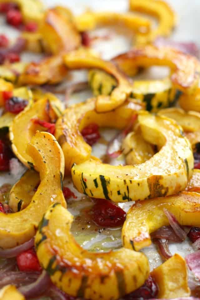roasted delicata squash slices on a baking sheet with cranberries