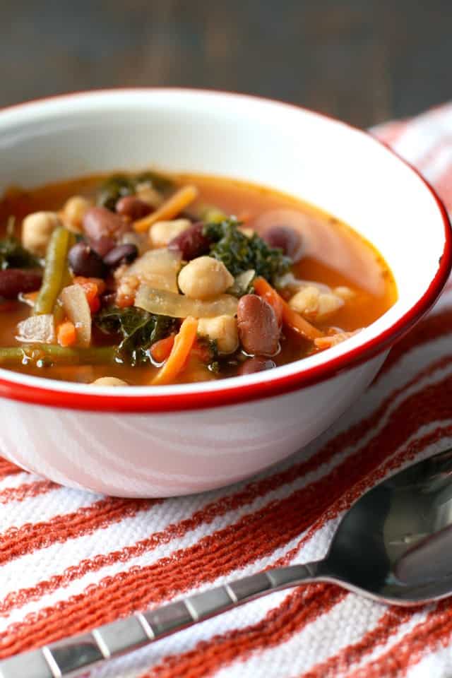 slow cooker minestrone soup in a white bowl on a striped towel