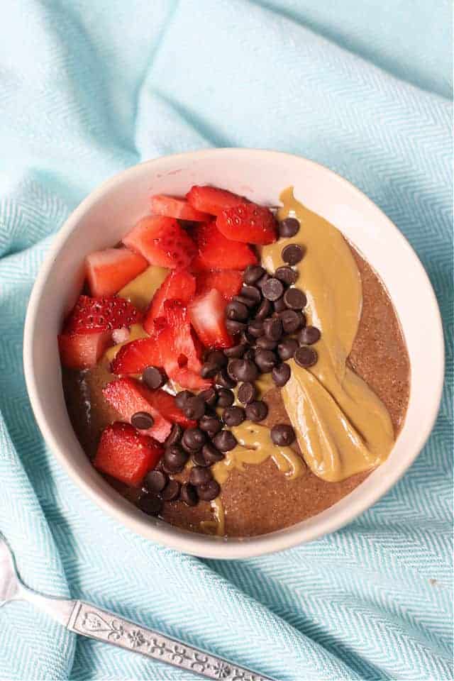 chocolate chia pudding in a bowl topped with strawberries and sunbutter