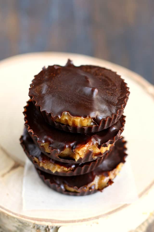 chocolate caramel cups stacked on a wooden tray