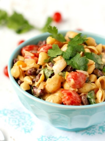 Southwest pasta salad with tri-color beans, tomatoes, cilantro, peppers, and a creamy, spicy, dressing. Delicious and easy!