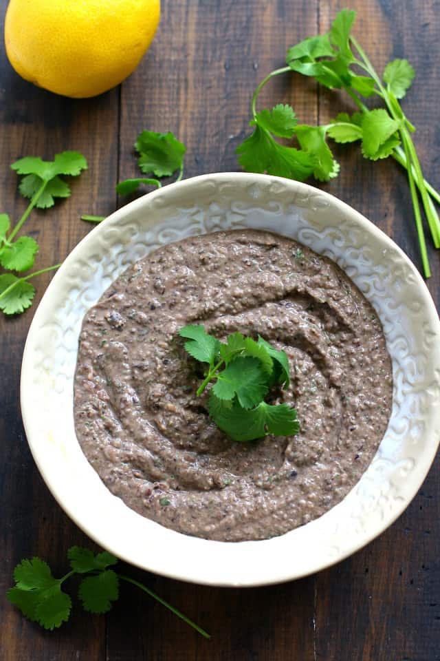 black bean hummus in a white bowl with cilantro leaves on top