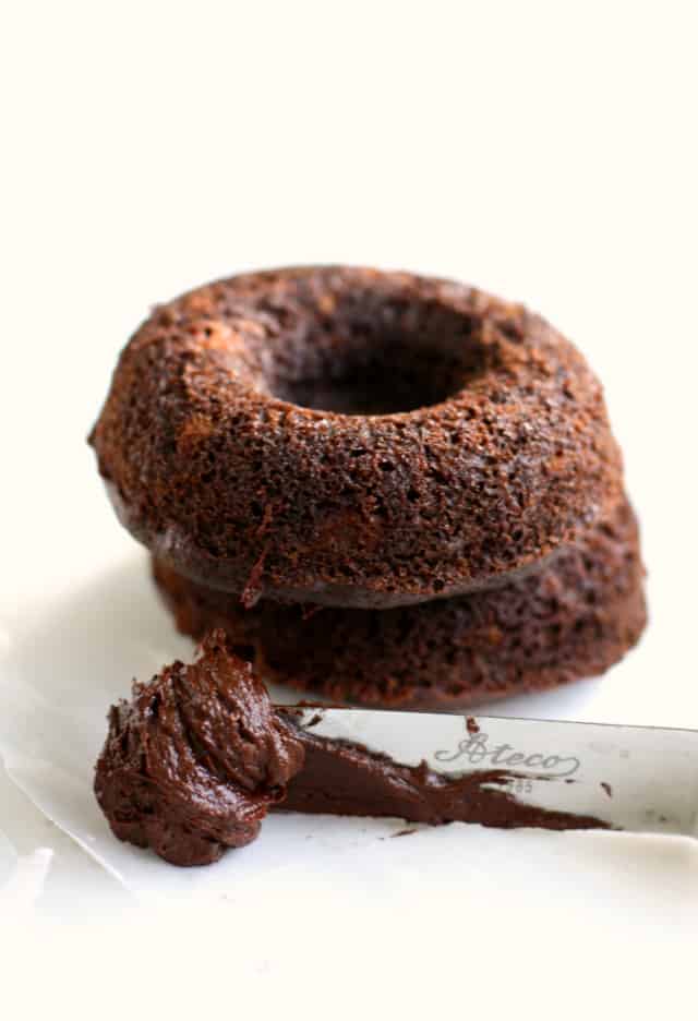 unfrosted chocolate donuts with a spatula with chocolate buttercream