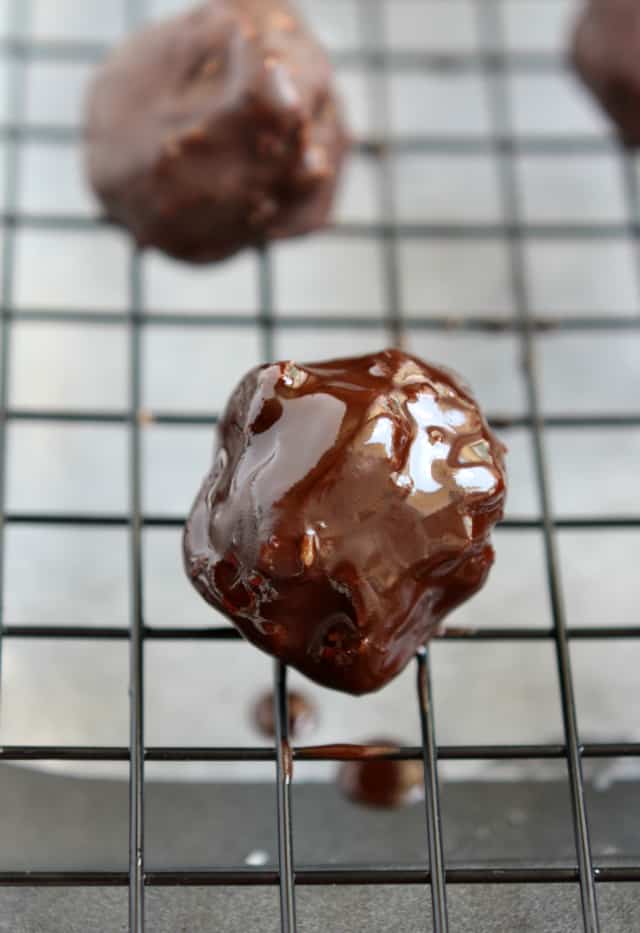 coconut candy balls covered in melted chocolate on a wire rack
