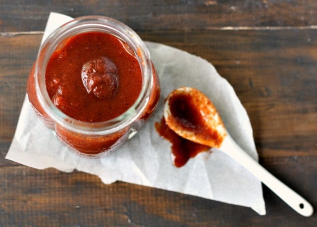 barbecue sauce in a small mason jar with a white spoon
