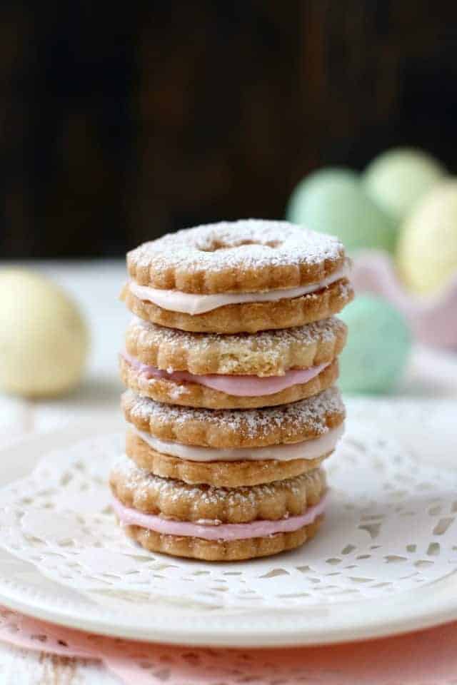 sugar cookie sandwiches stacked on a plate with easter eggs in the background