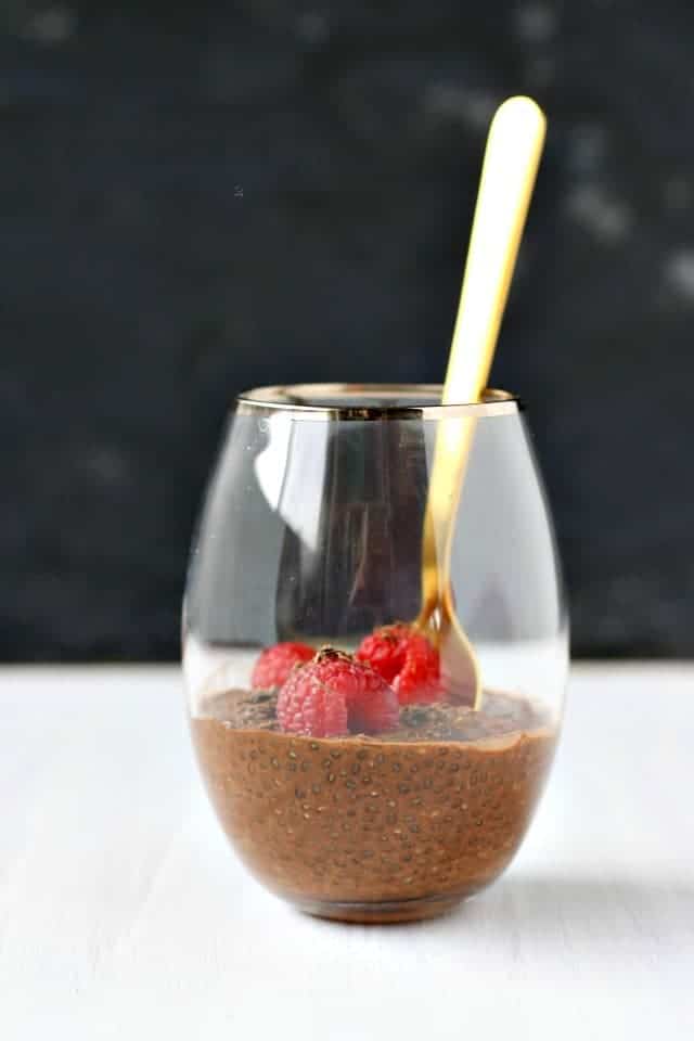 vegan chocolate chia pudding in a clear glass with a gold spoon
