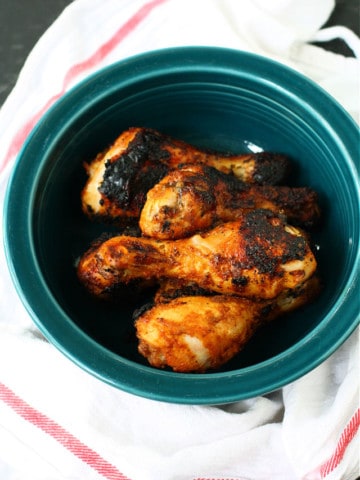 grilled chicken legs in a teal bowl