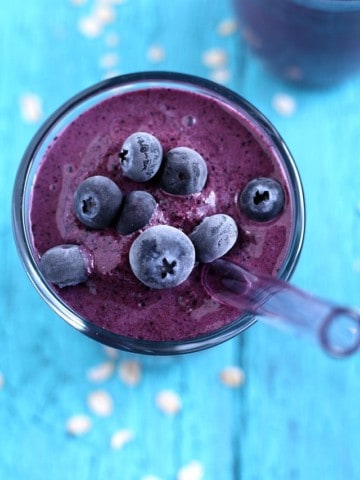blueberry oatmeal smoothie in glass with straw