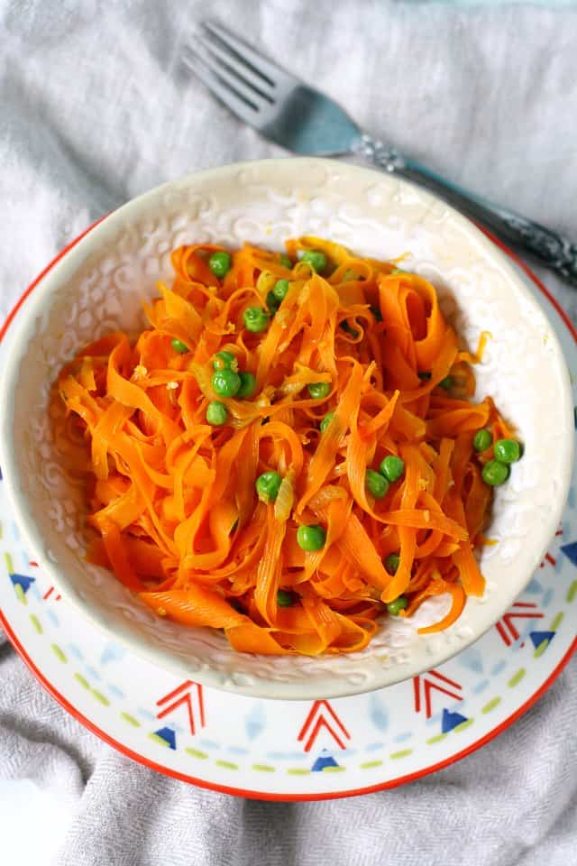 carrot noodles with peas in a white bowl
