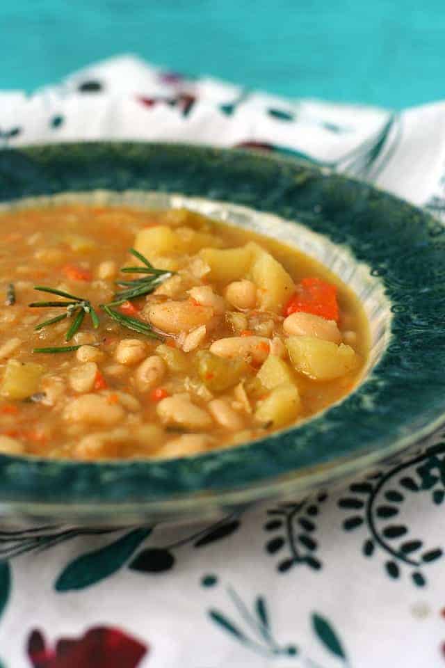 rosemary white bean soup in a teal soup bowl on a floral napkin