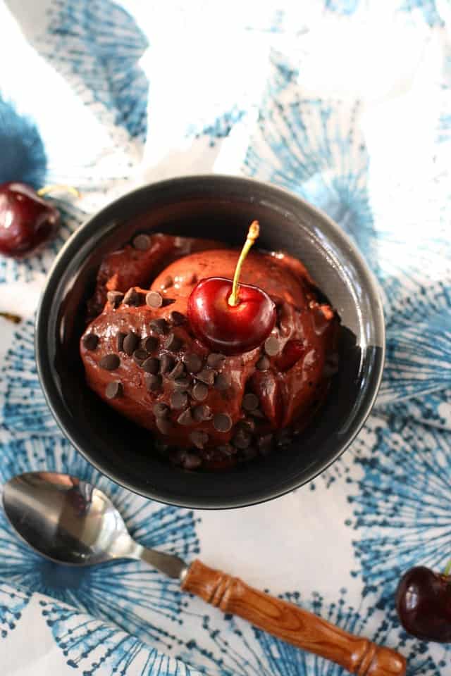 chocolate cherry nice cream in a bowl with a wooden handled spoon