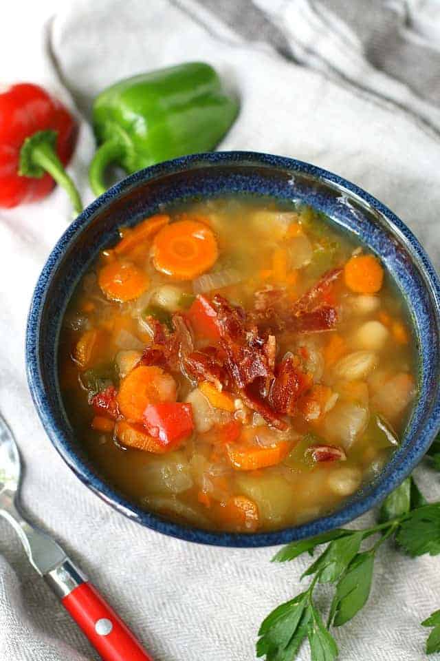 slow cooker bean vegetable soup with bacon in a blue bowl