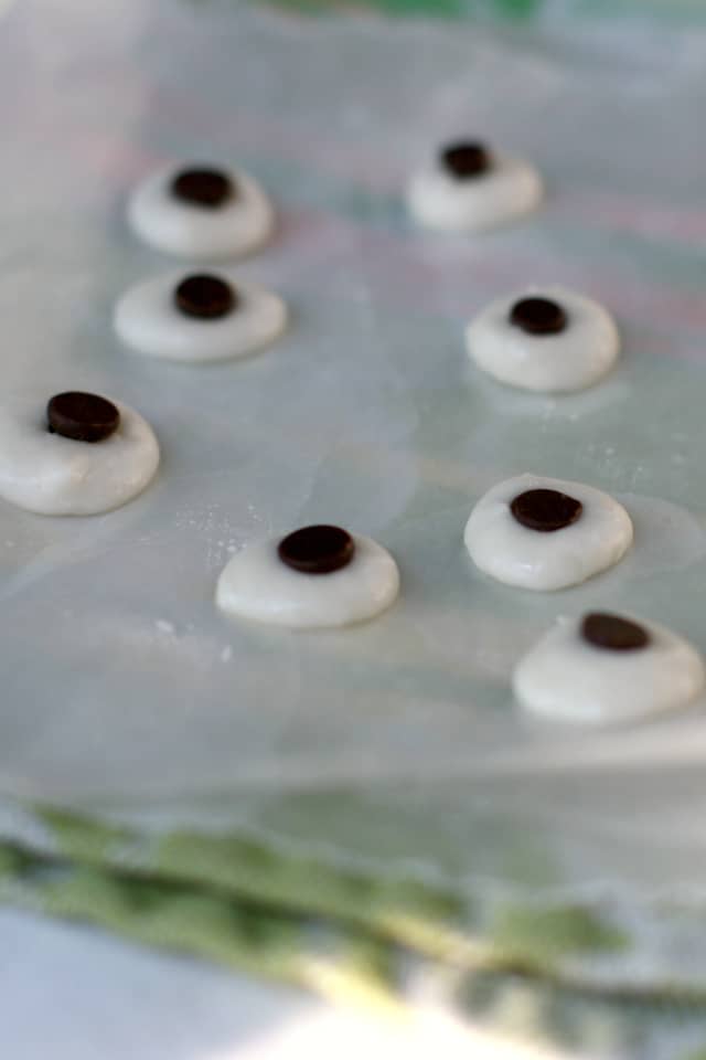 eyes made of frosting and chocolate chips on a piece of waxed paper