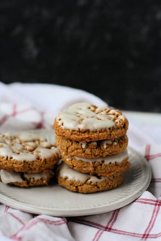iced oatmeal cookies stacked on a plate