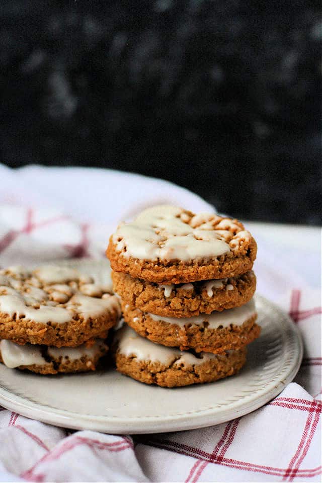 iced oatmeal cookies stacked on a white plate