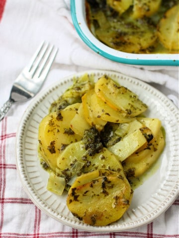 serving of kale scalloped potatoes on a white plate with a plaid napkin