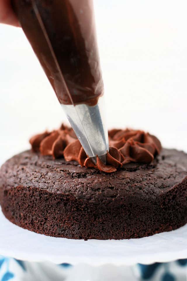 chocolate frosting being piped onto a chocolate cake