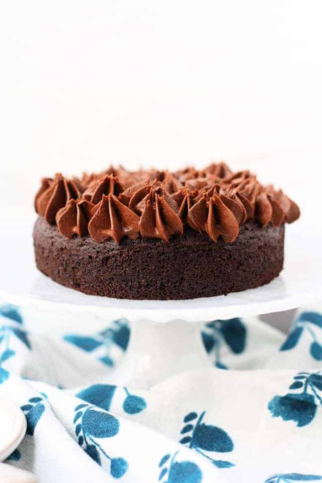 small chocolate cake on a white cake stand