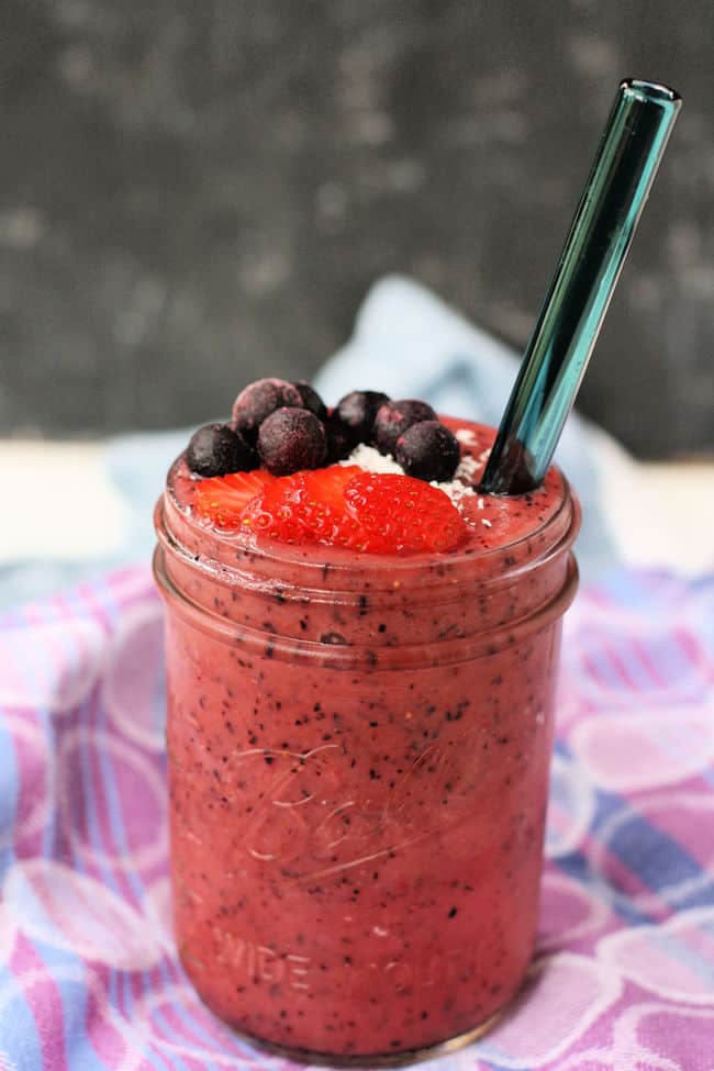 berry smoothie in a mason jar with a glass straw