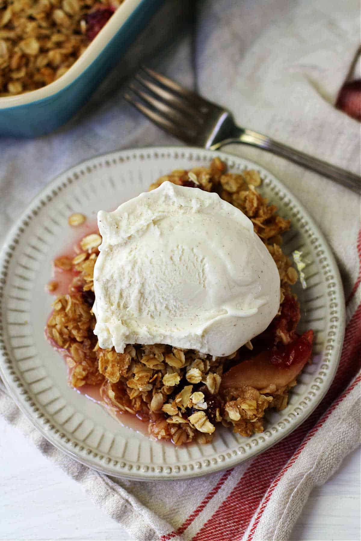 Crujiente de manzana y arándano con helado de vainilla en un plato