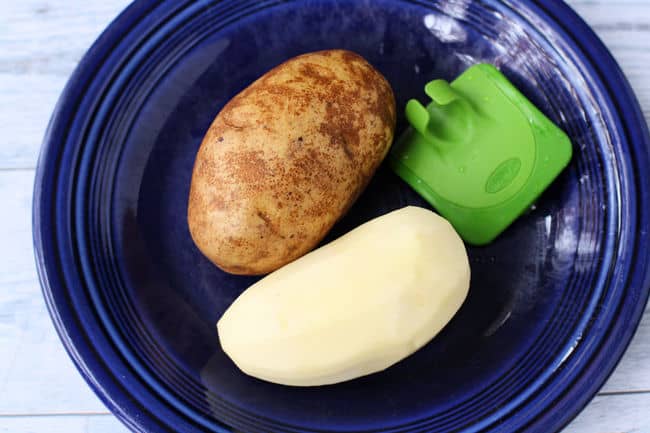 potatoes and a peeler on a plate