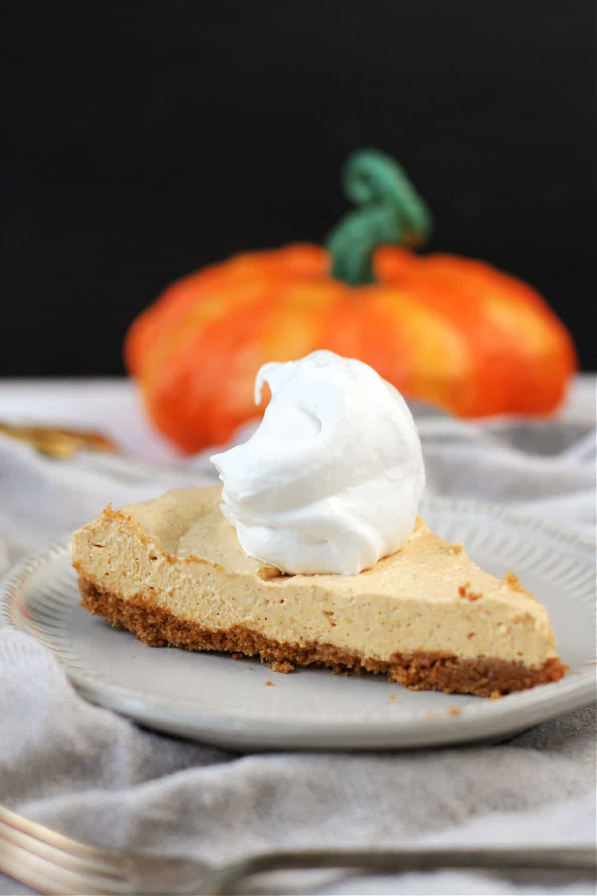 vegan pumpkin cheesecake on a plate with a spoonful of whipped topping