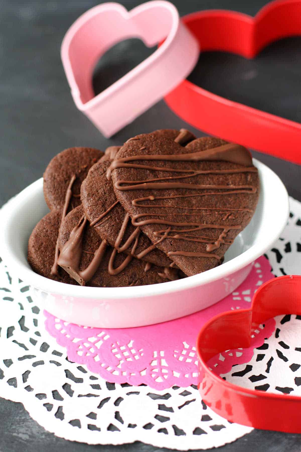 gluten free vegan chocolate heart cookies in a white bowl on doilies