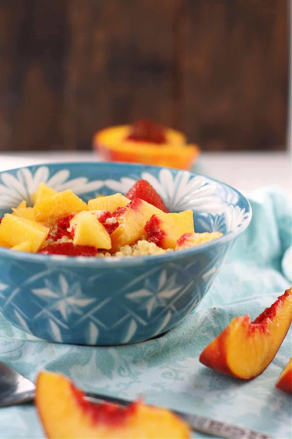 quinoa breakfast cereal with peaches in a blue and white bowl