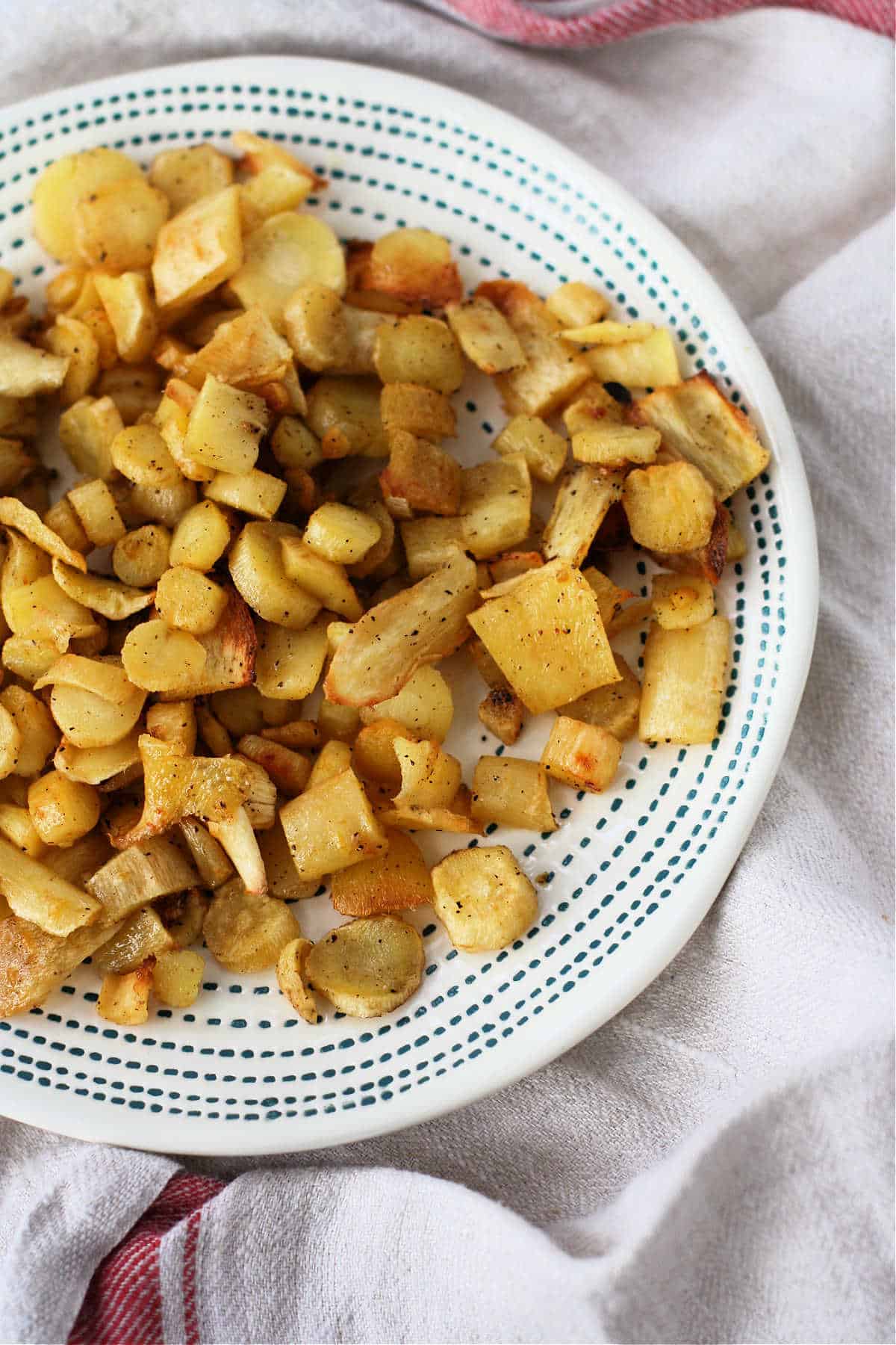 roasted parsnips with garlic on a white and blue plate