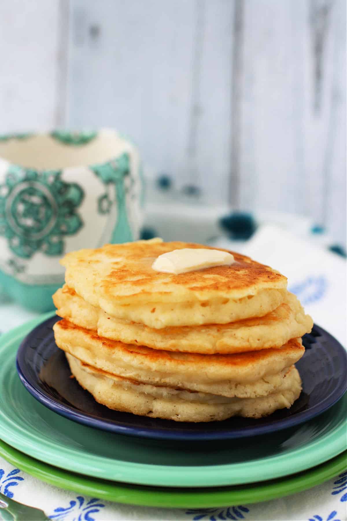 fluffy vegan pancakes with buttery spread on a blue plate