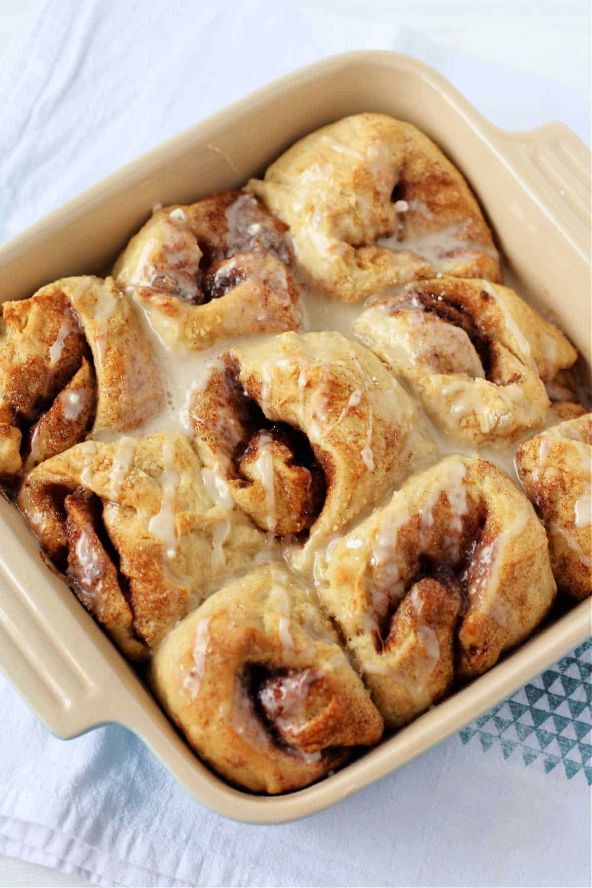 vegan cinnamon rolls with icing in a baking pan