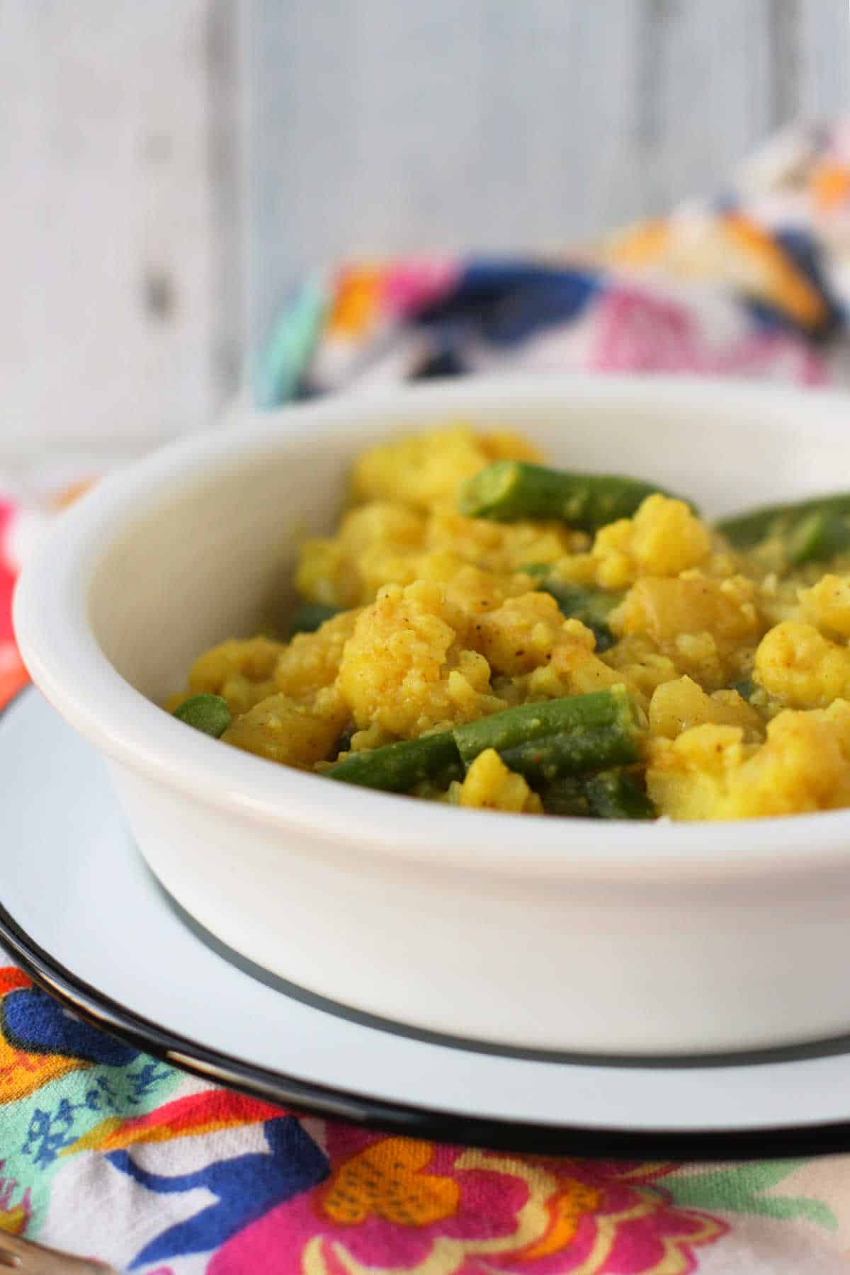 dairy free cauliflower curry with green beans in a white bowl