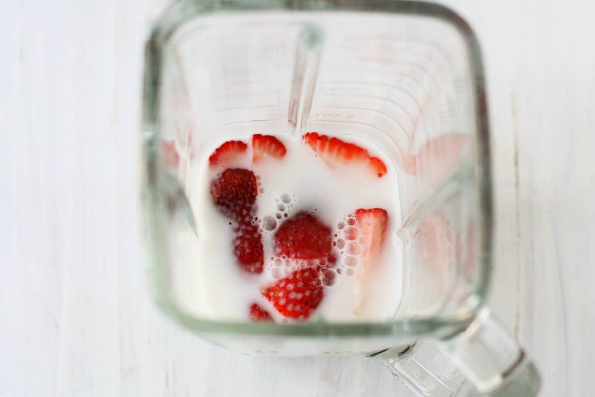 strawberries and milk in a blender