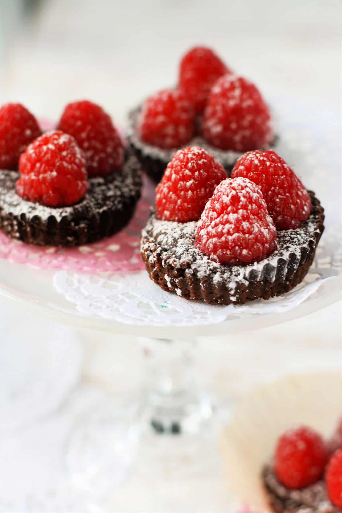 chocolate raspberry tarts with cookie crust on doilies