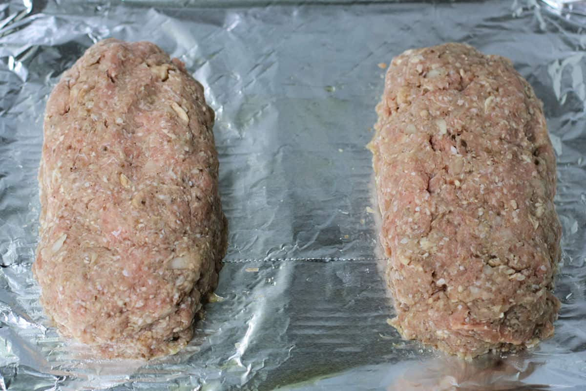 two uncooked meatloaves on a baking sheet