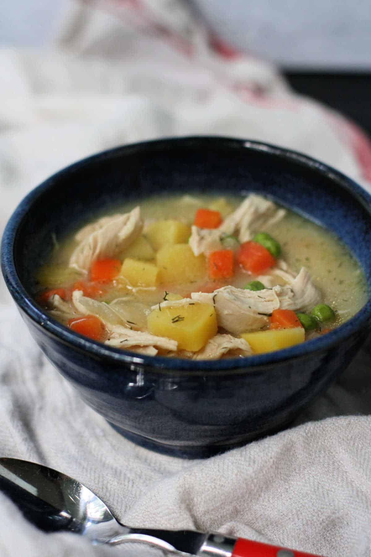 chicken soup with potatoes and carrots in a blue bowl