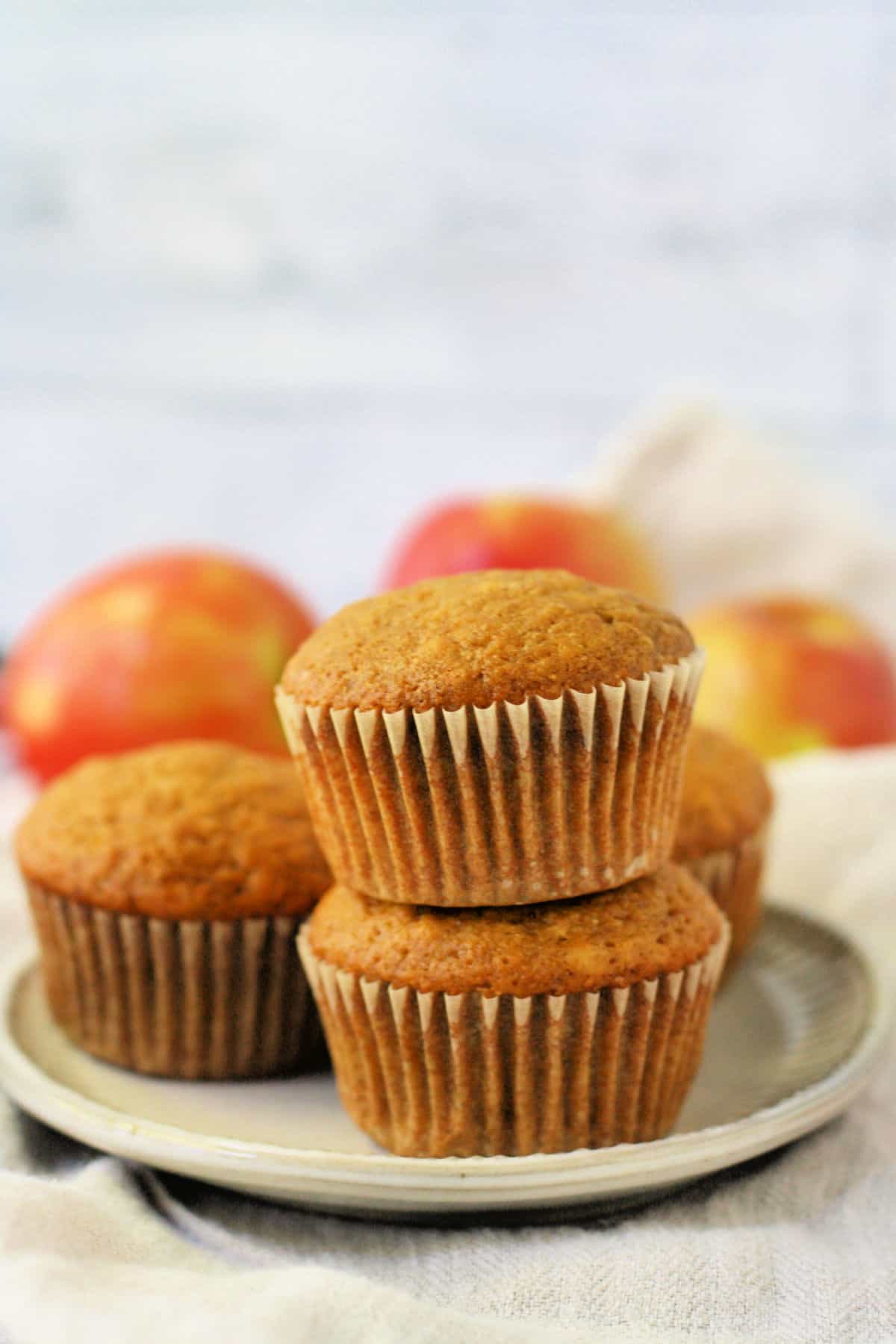 vegan applesauce muffins stacked on a white plate